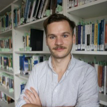 in library wearing shirt with arms folded