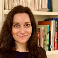 softly smiling, book shelf in background