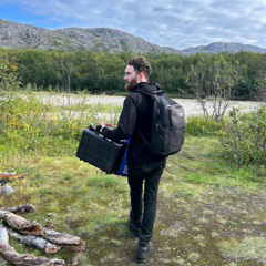 facing partly away holding field equipment