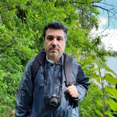 camera hanging from neck, dark jacket and green leaves